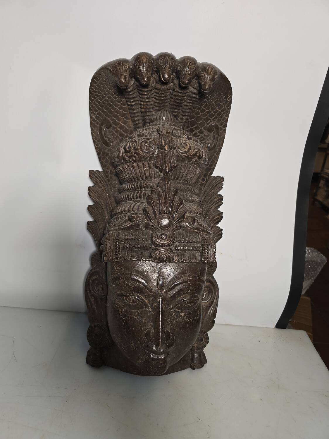 Ancient Indian carved wooden mask sculpture of a deity with a cobra.