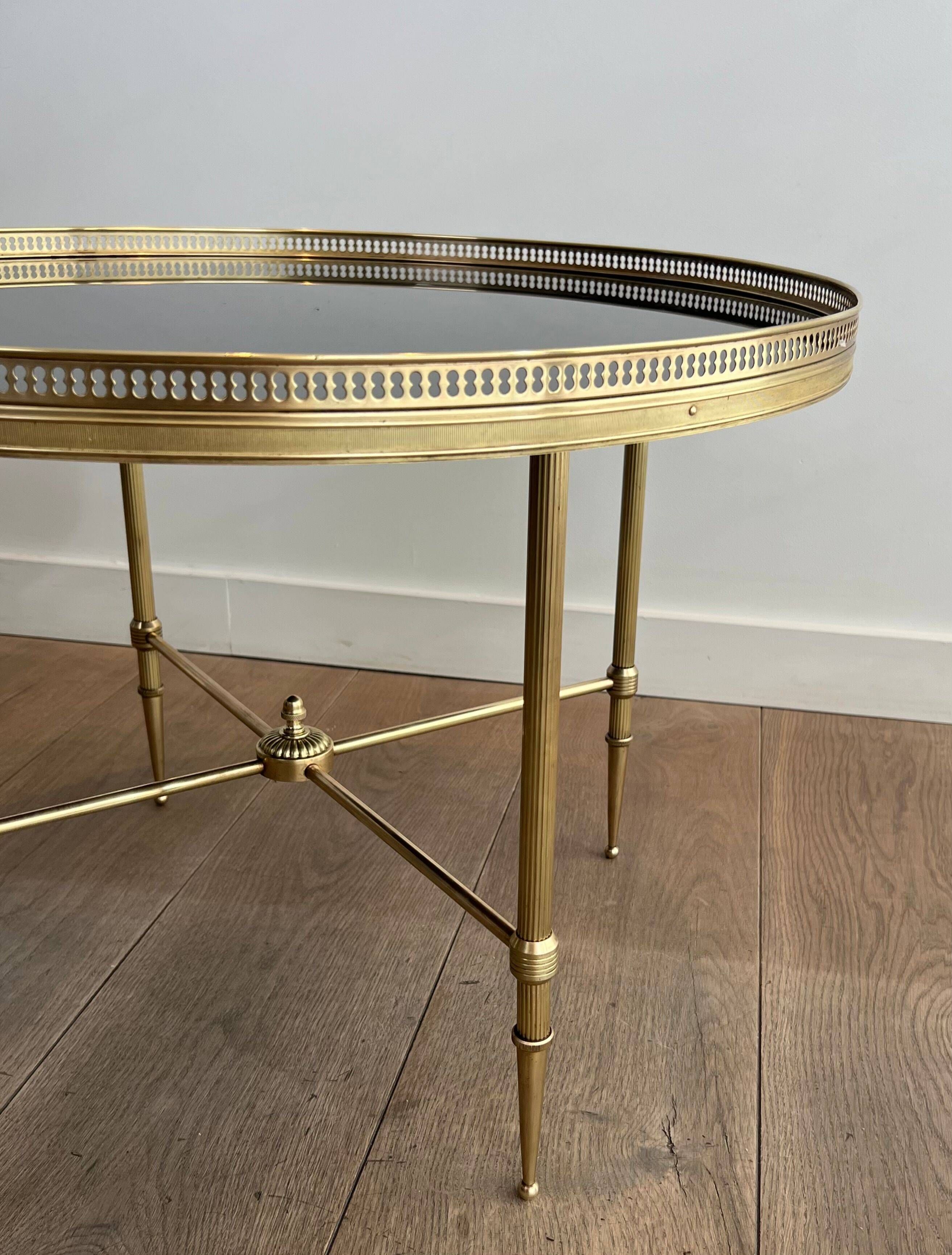 Round coffee table in brass with a black lacquered glass top from Maison Jansen.