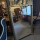 Large Empire-style mirror in dark green painted wood and gilded stucco.