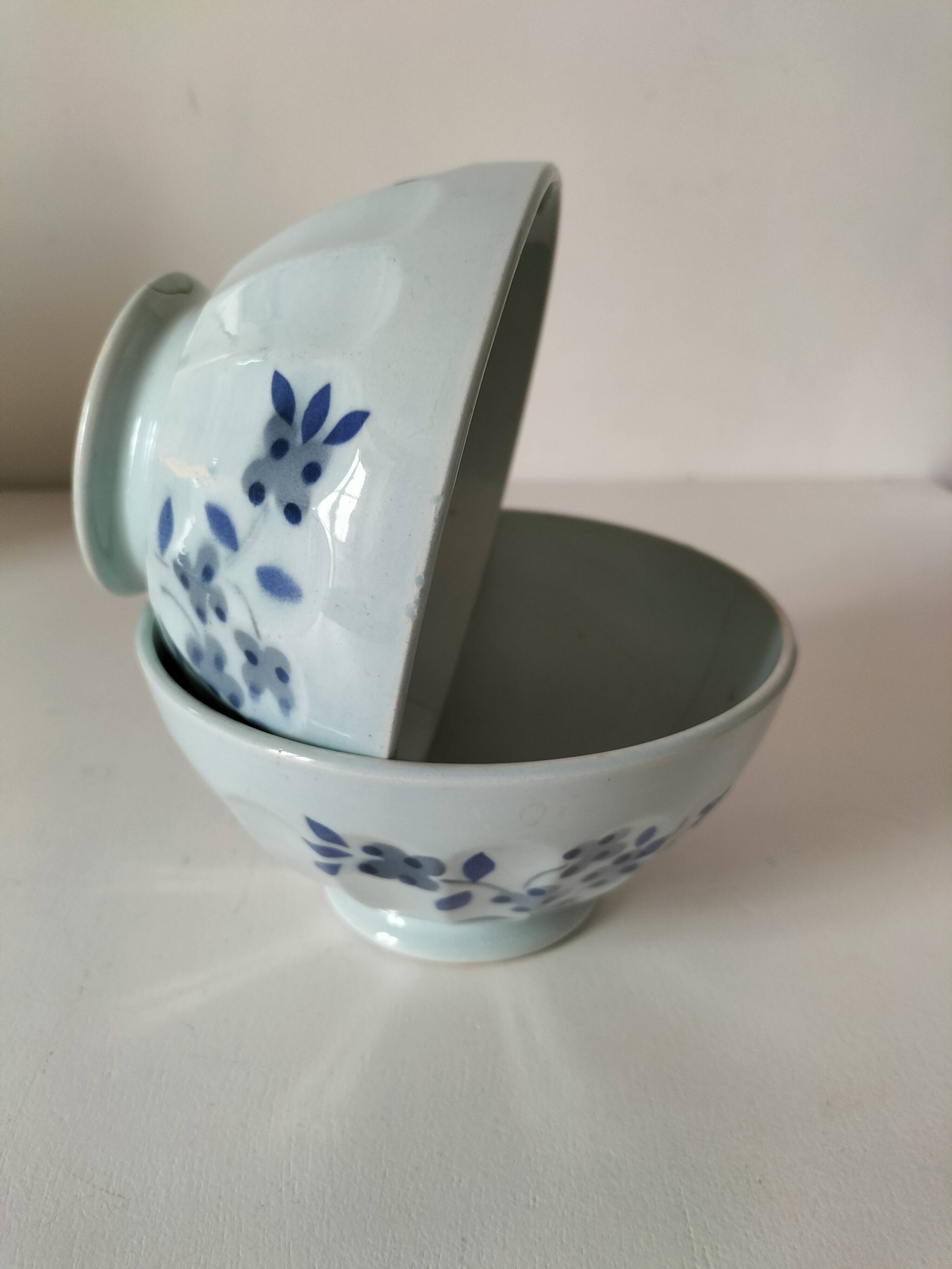 Two vintage farm bowls on a pale blue pedestal with floral decoration.