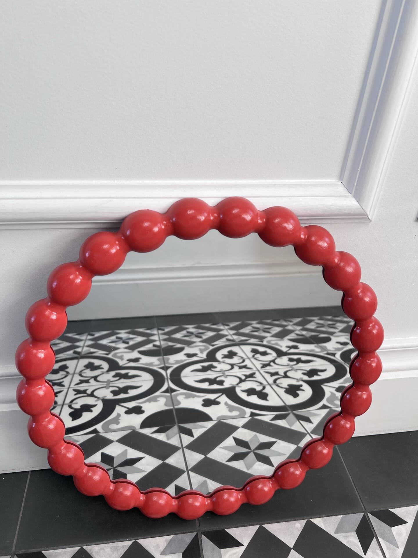 Round wall mirror with red beads in vintage retro design style.
