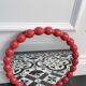 Round wall mirror with red beads in vintage retro design style.
