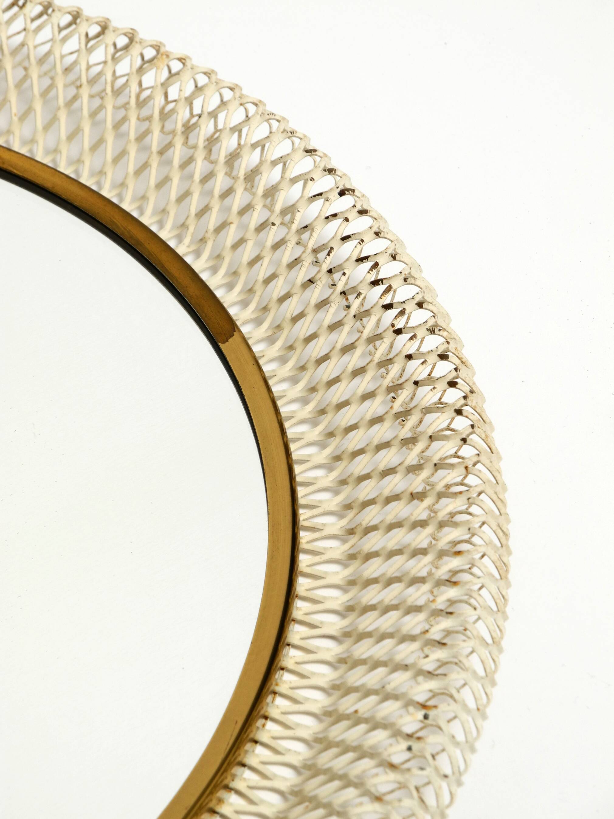 Mid Century Modern round wall mirror with a white expanded metal frame