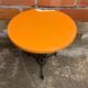 Vintage bistro table with black cast iron base and orange bakelite top, 1950s