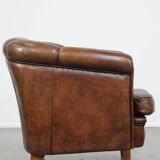 Fauteuil club en cuir de mouton foncé avec passepoil noir
