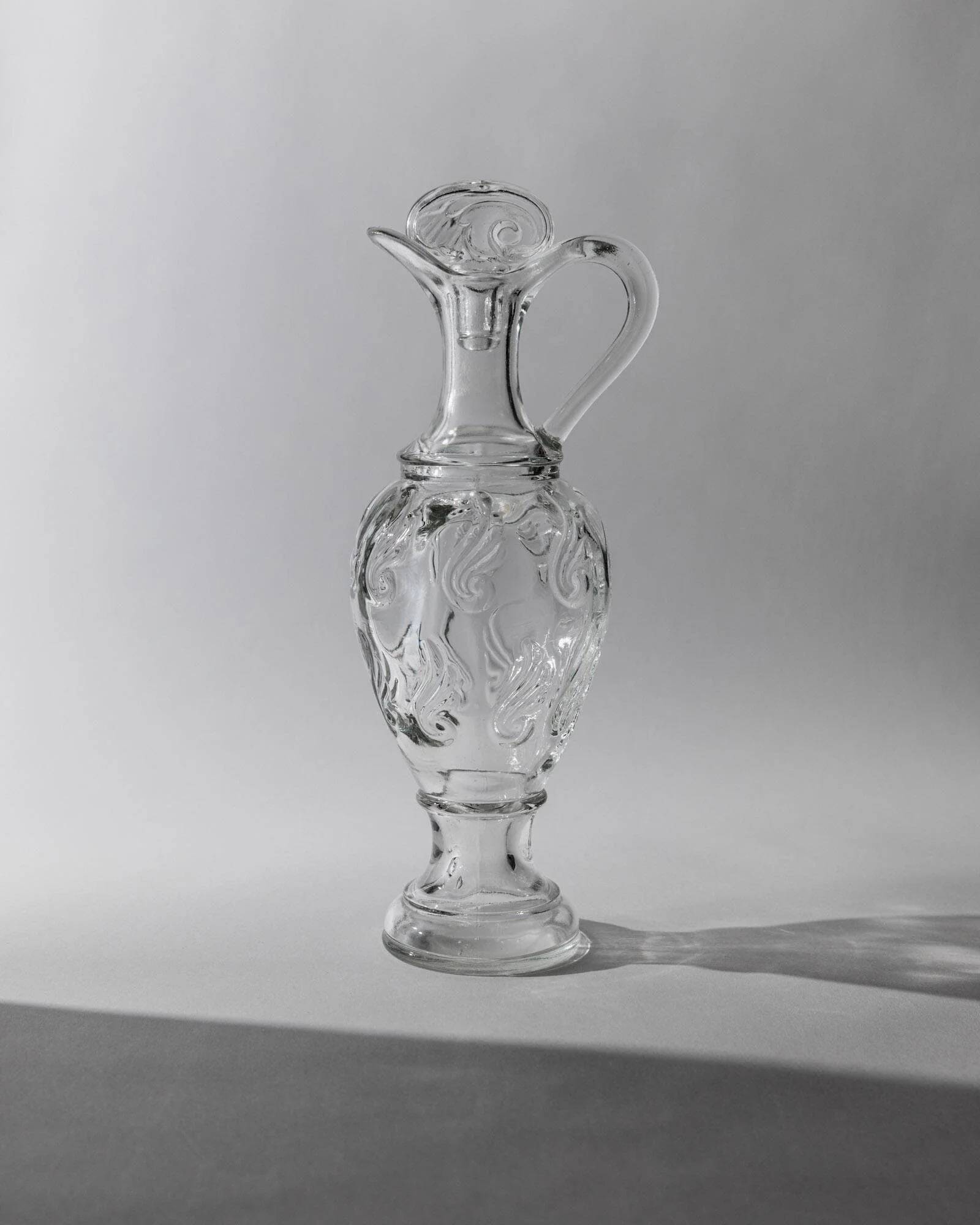 Vintage pressed glass carafe from the 1960s, clear sculptural glass with textured patterns and a stopper.
