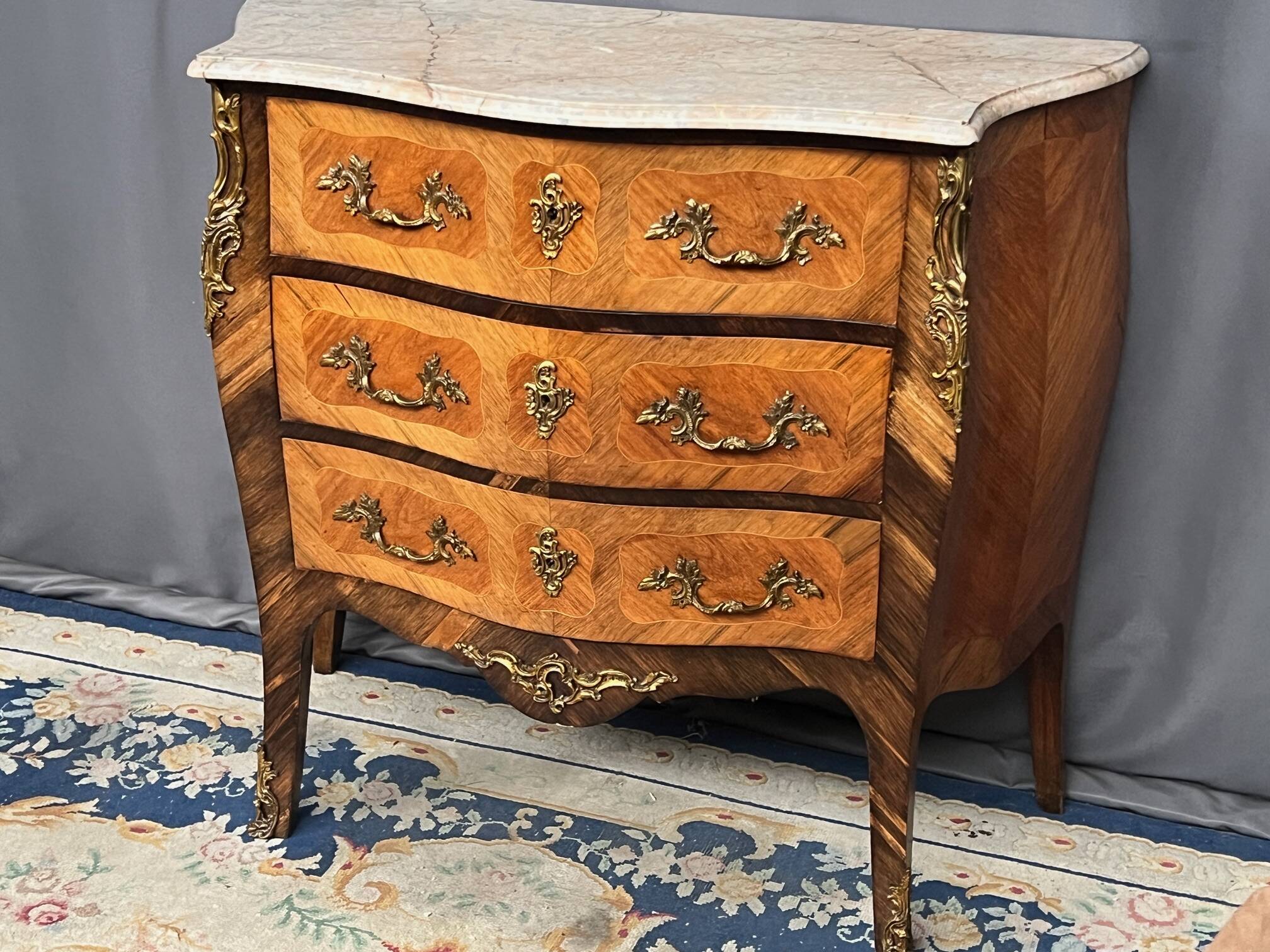 Louis XV style commode with rosewood veneer, gilded bronze mounts, and marble top.