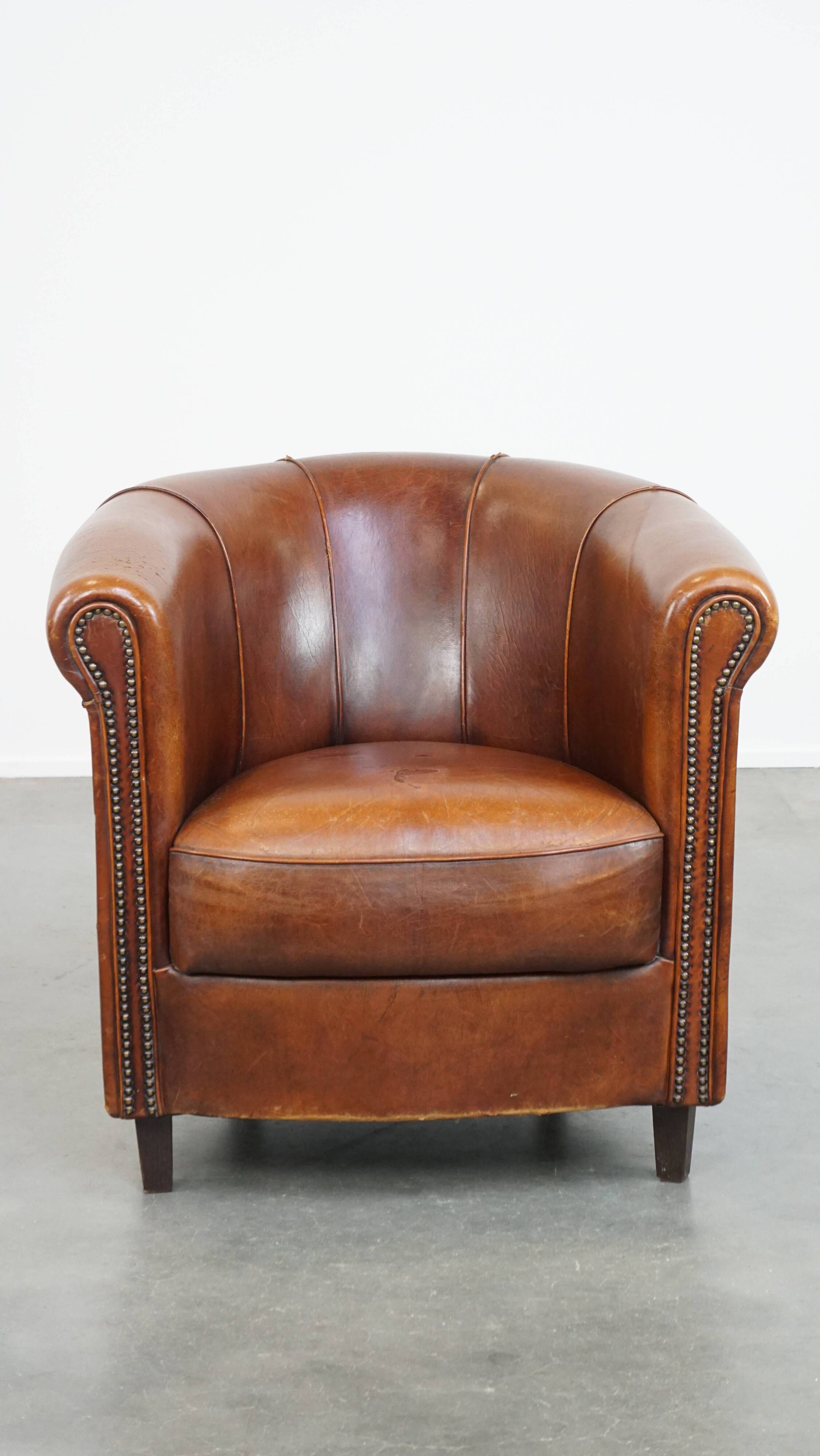 Sheep leather club chair in a cognac color and finished with piping