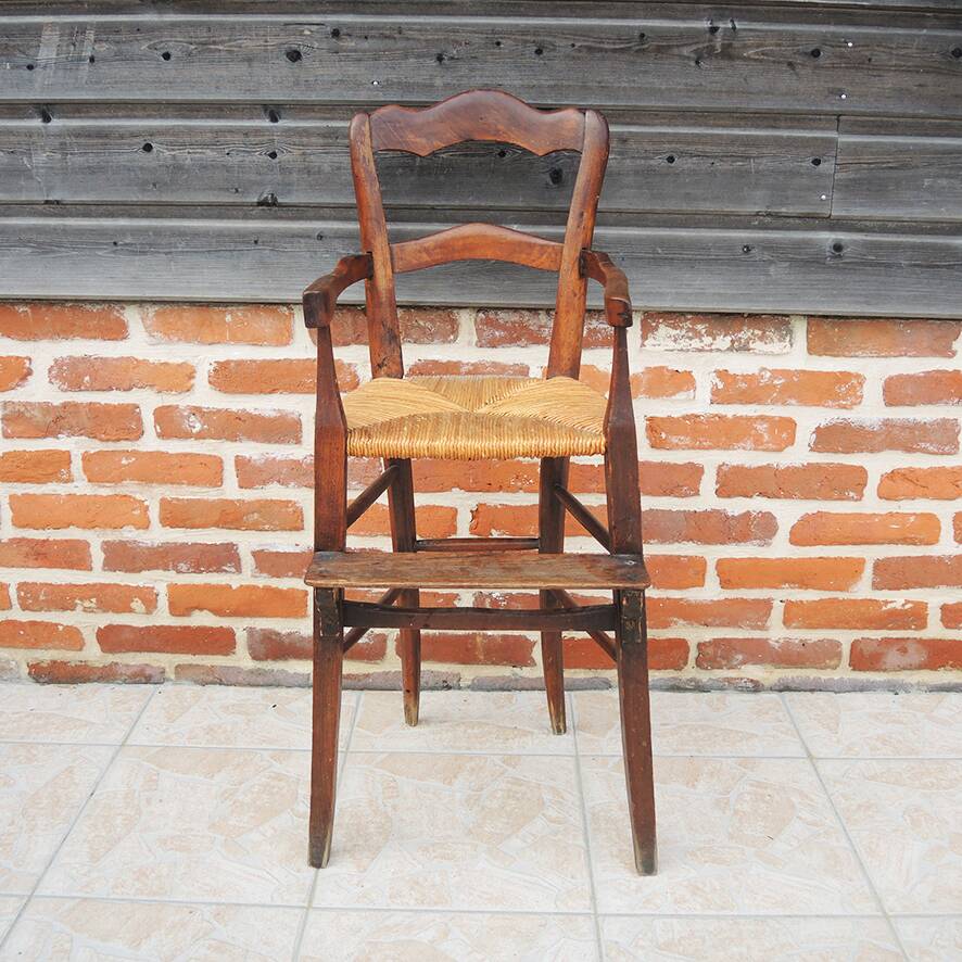Old wooden high chair for children with straw.