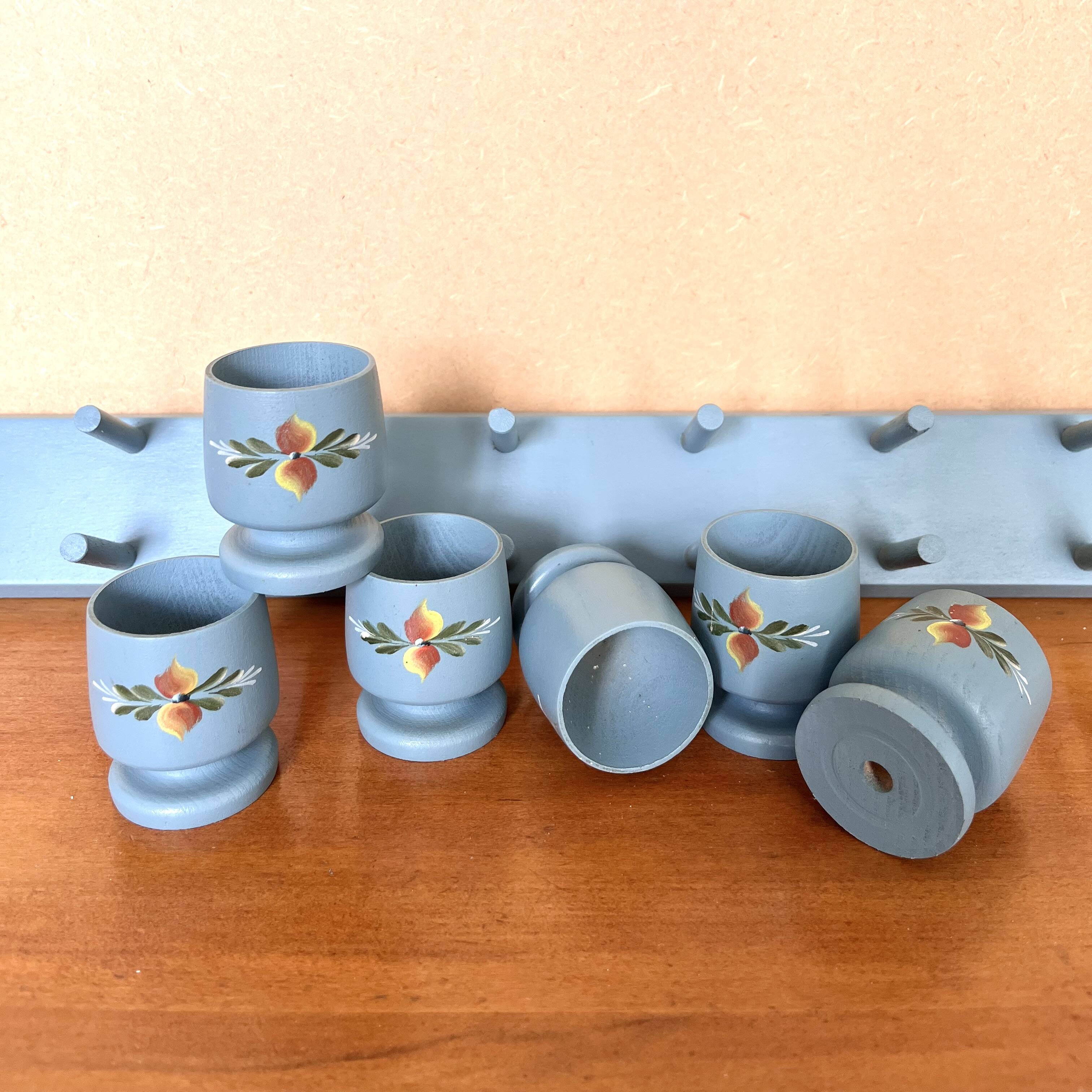 6 vintage egg cups on a wall shelf