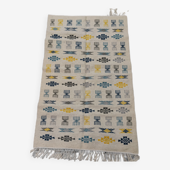 White carpet with Berber patterns gray blue and yellow woven hands