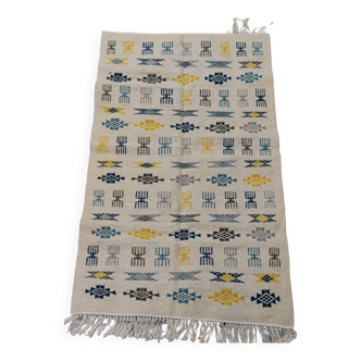 White carpet with Berber patterns gray blue and yellow woven hands