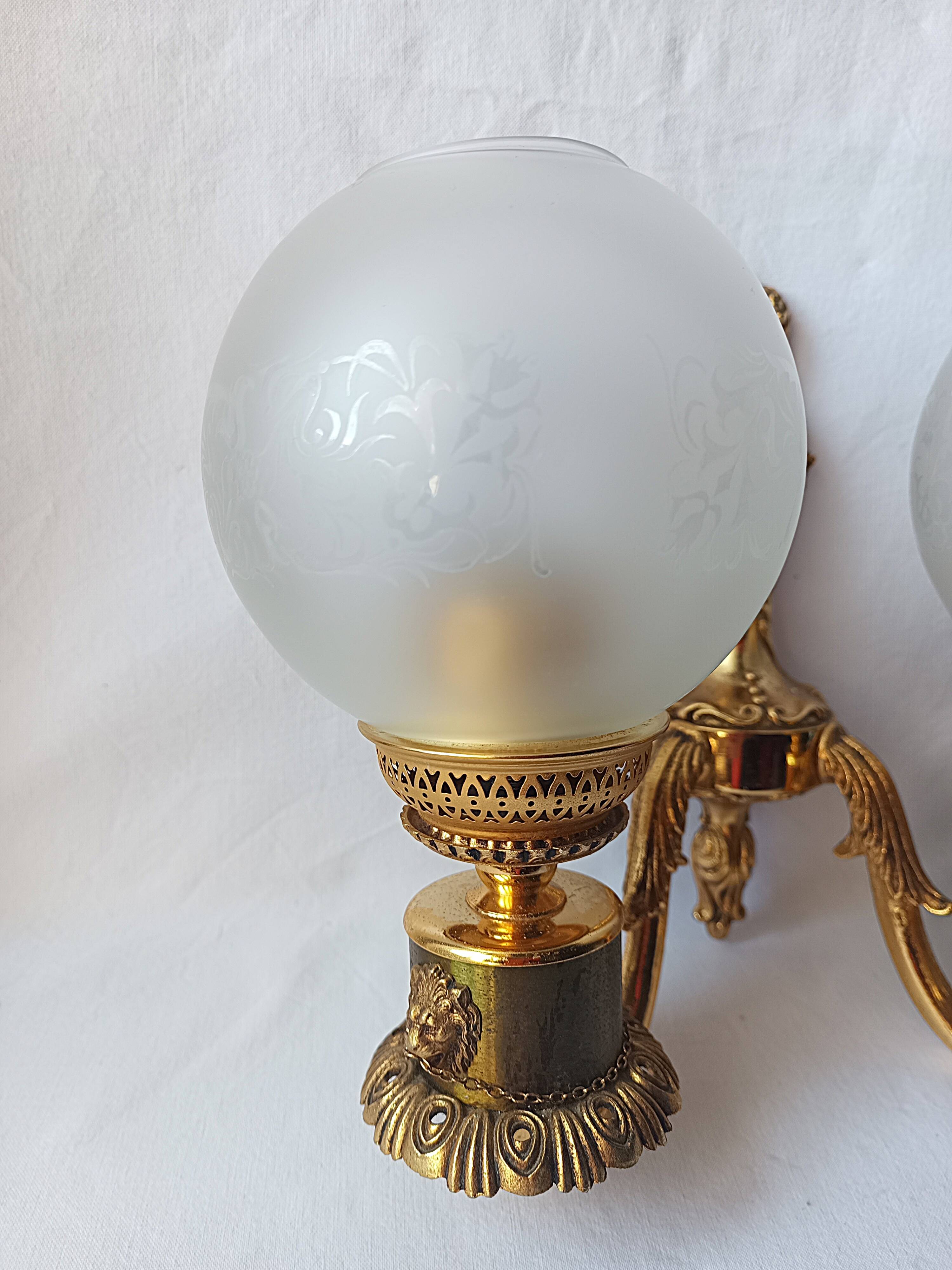 Wall lamp in gilded bronze with a lion's head and engraved globe.