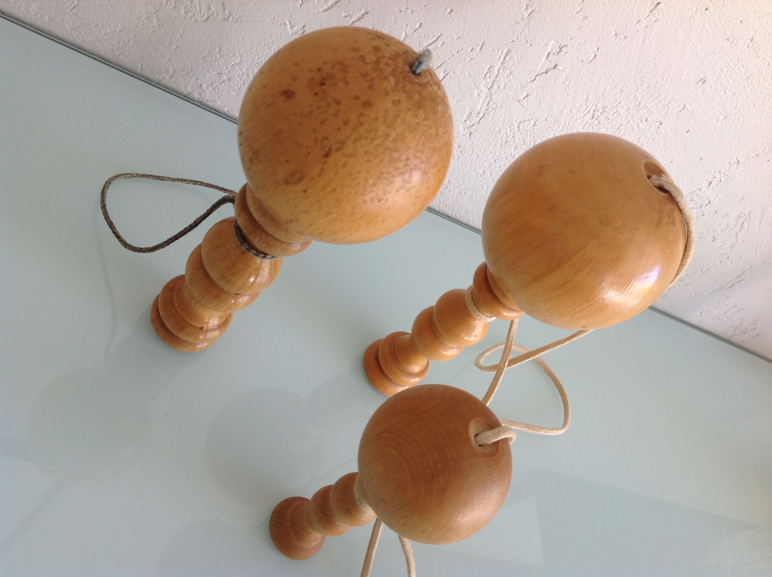 Suite de trois anciens bilboquets en bois clair
