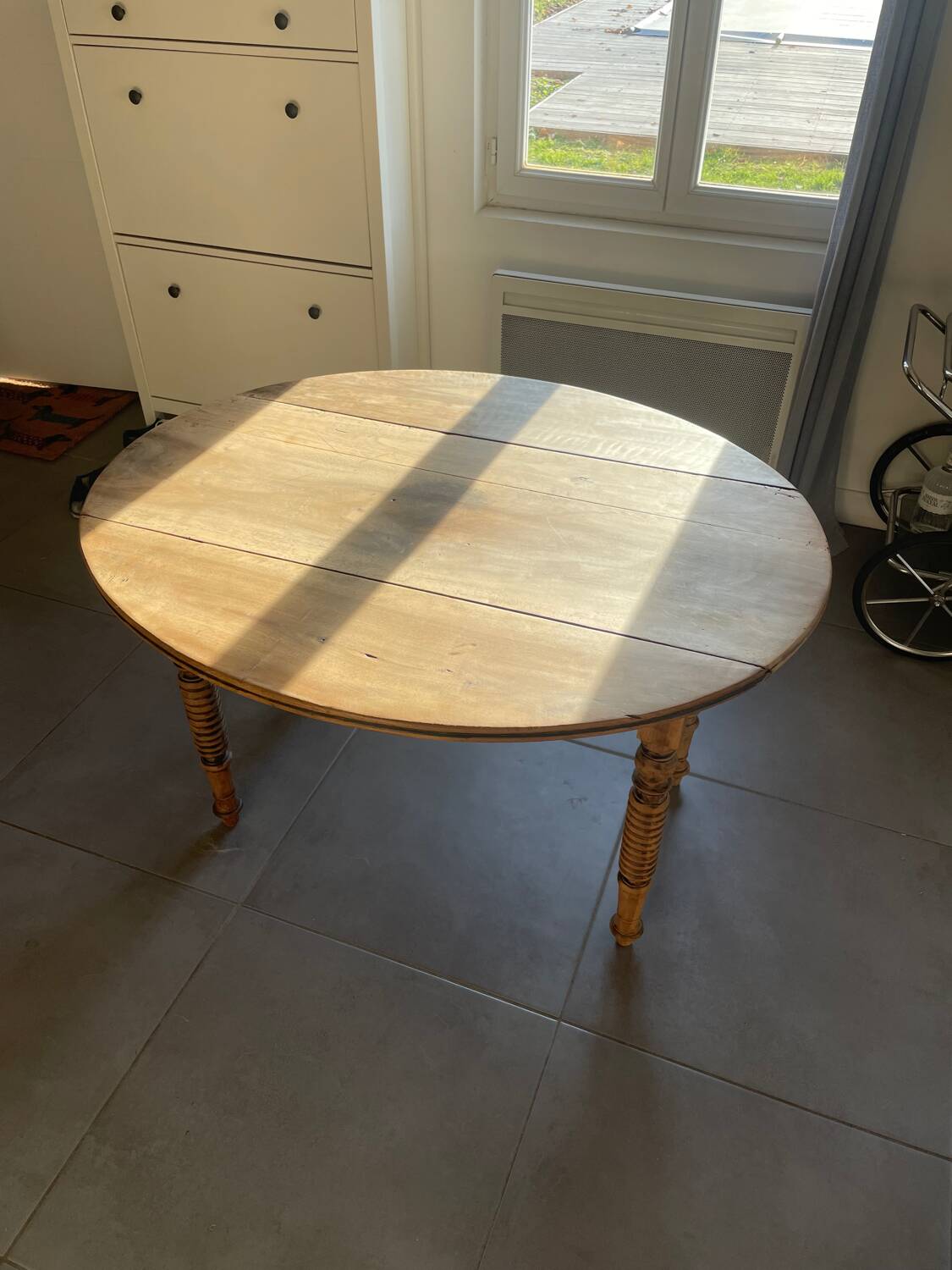Oval wooden table with drop-leaf edges.