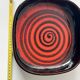 Large decorative ceramic catchall with red and black spiral pattern.