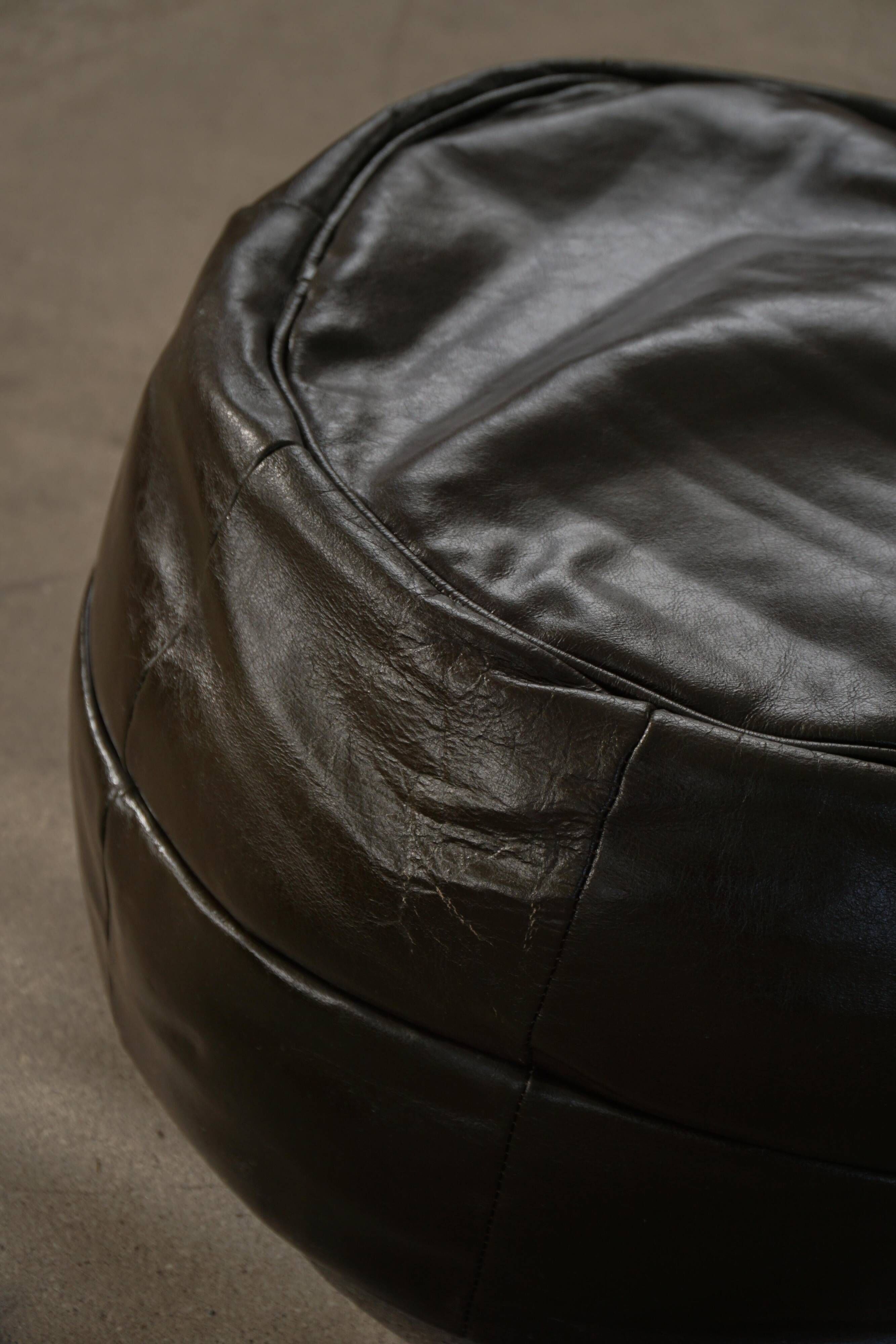 Vintage black leather pouf/ottoman with a rounded shape, French mid 20th Century.