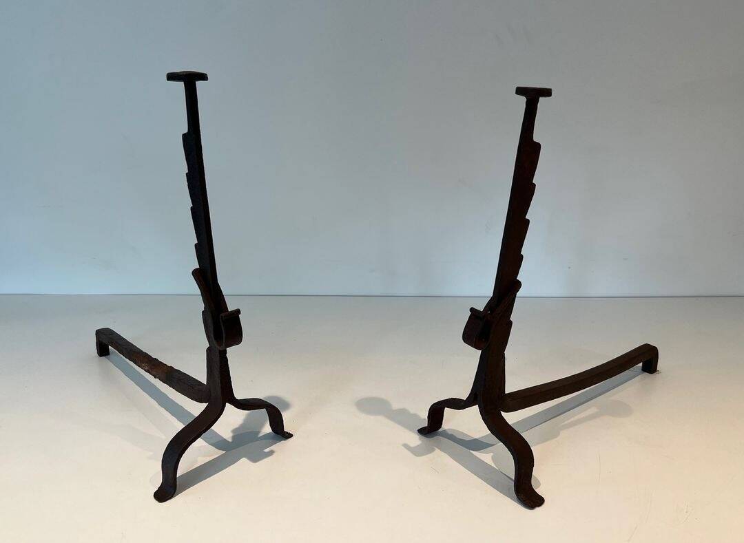 Pair of wrought iron andirons with adjustable supports and tripod feet.