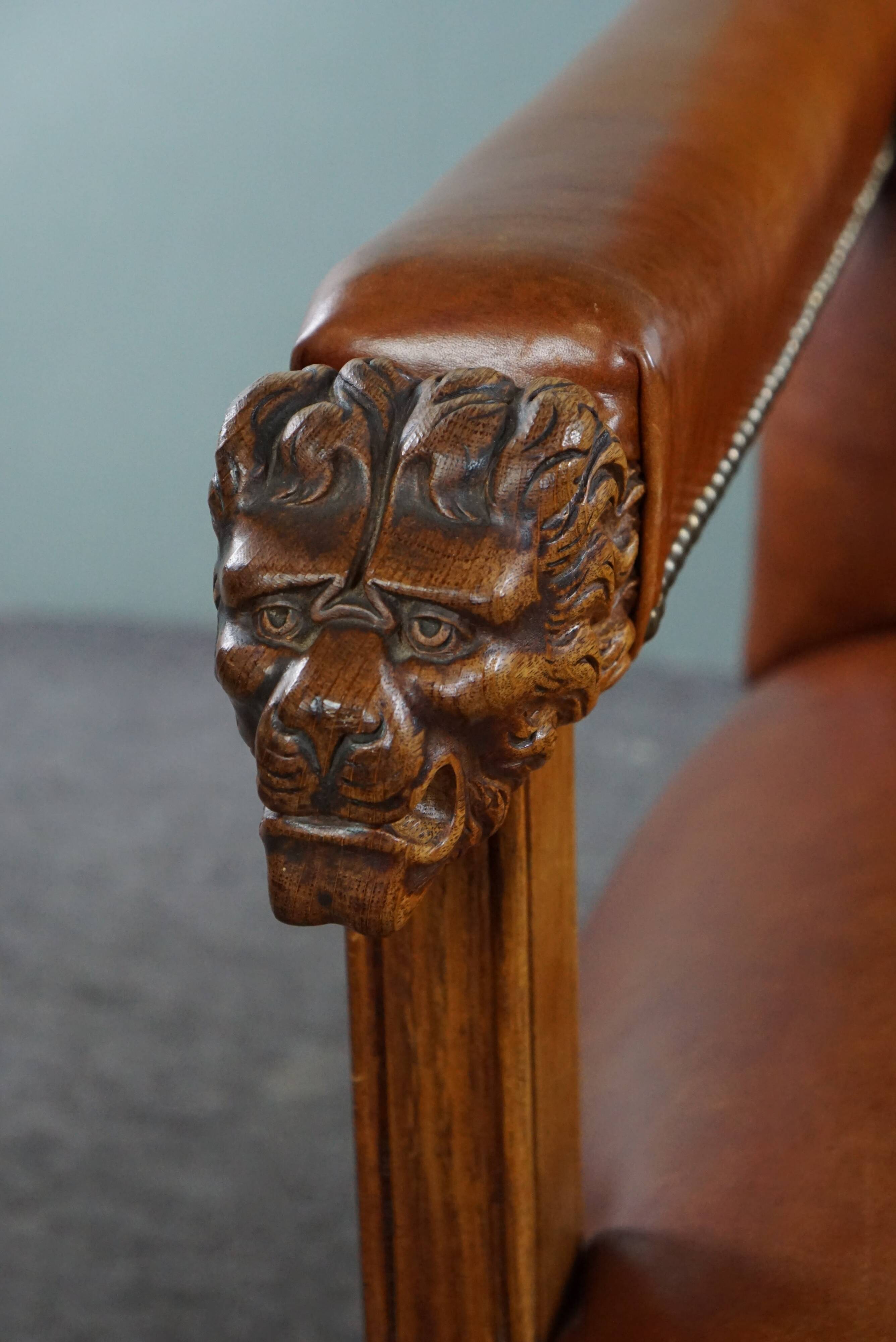 Armchair with lion heads reupholstered in cognac-colored cowhide leather