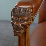 Armchair with lion heads reupholstered in cognac-colored cowhide