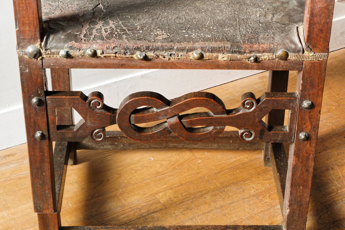 Antique armchair in walnut and studded leather, 17th century