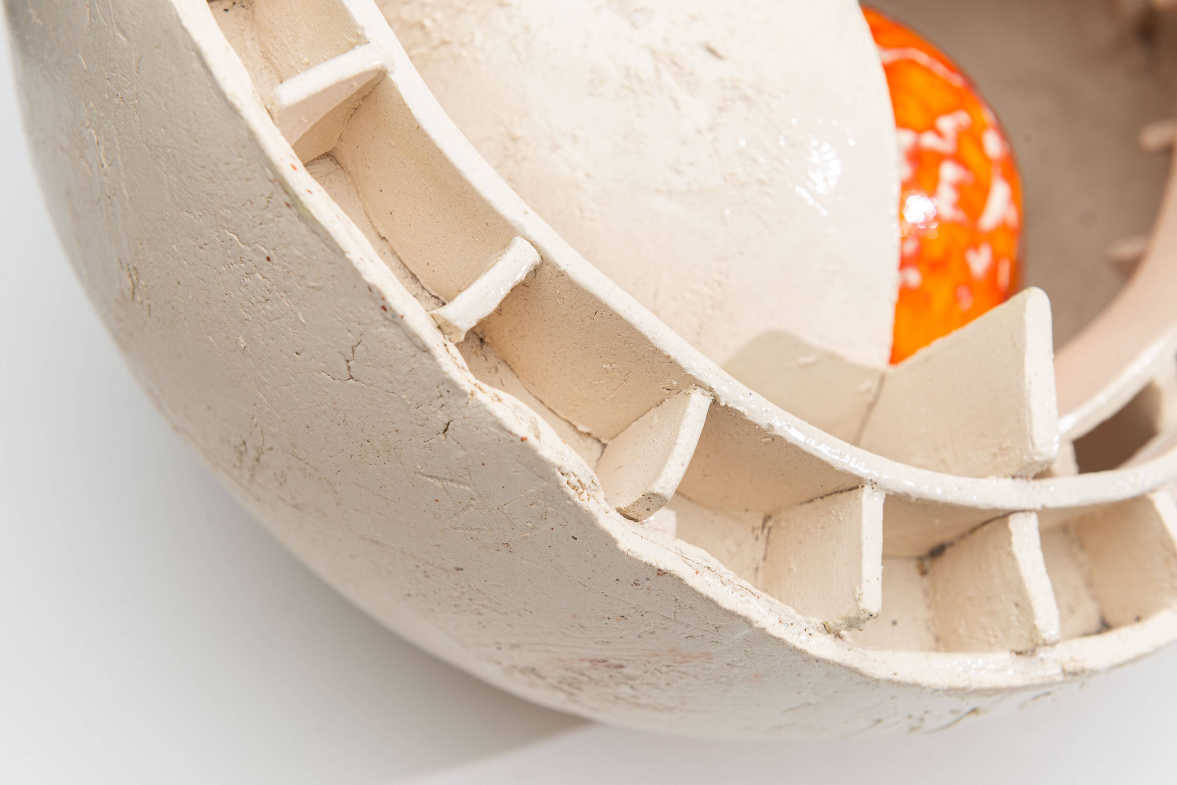 Sculpture en céramique abstraite avec un noyau orange.