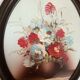 Oval painting of a bouquet of flowers, oil on panel.