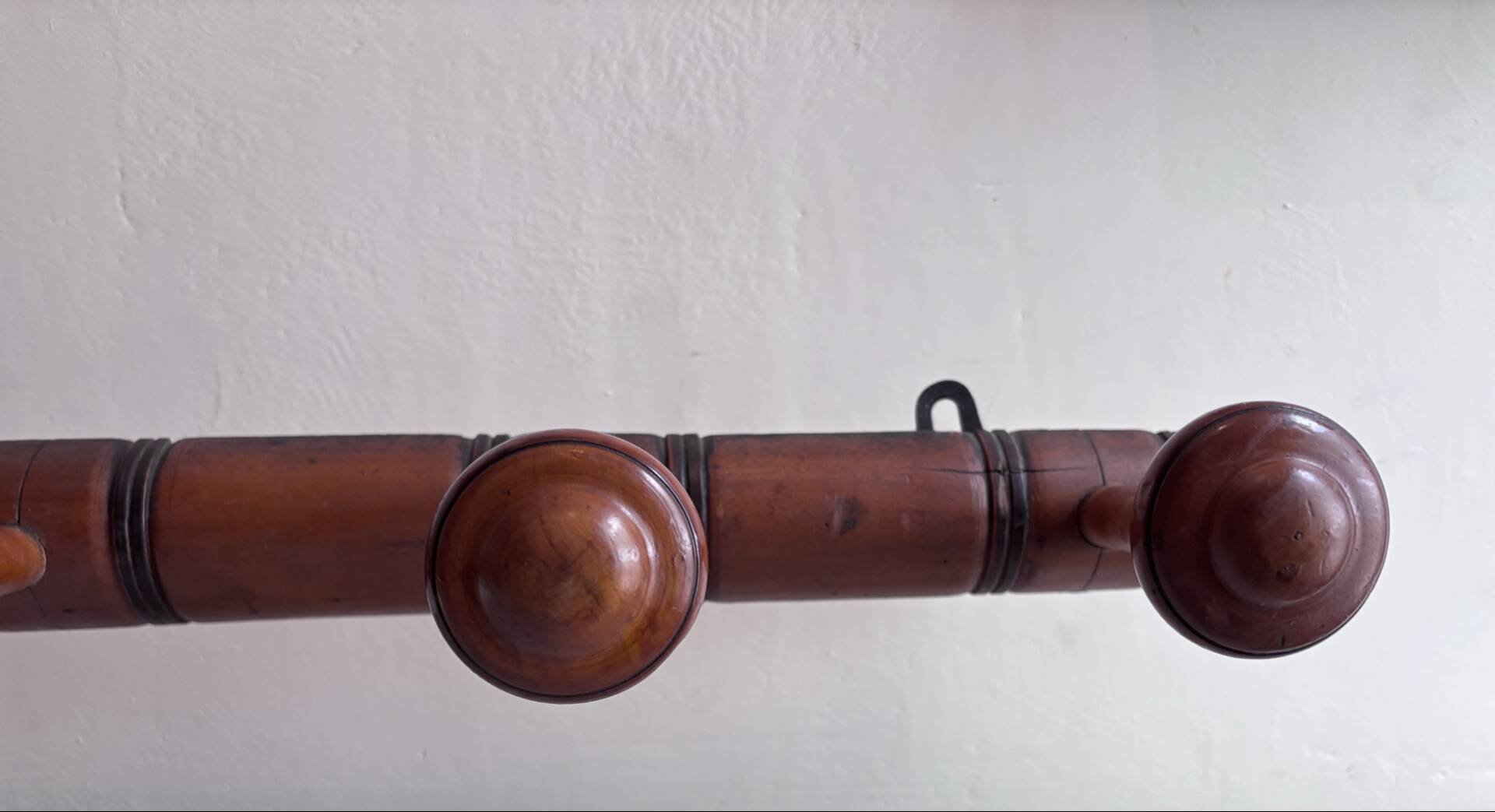 Wall-mounted coat rack with 8 turned wooden hooks in faux bamboo style.