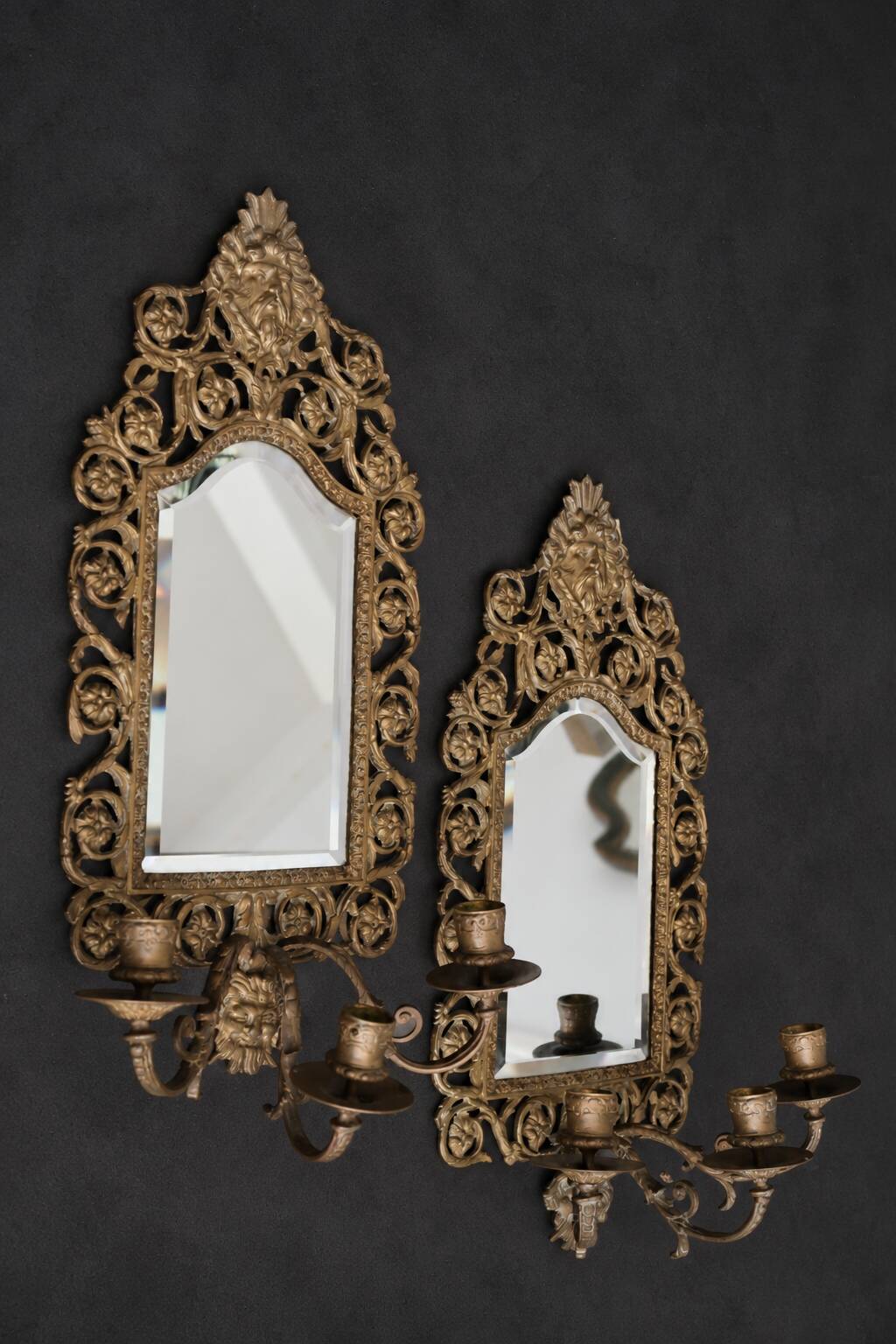 Pair of mirror wall sconces with brass candle holders.