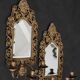 Pair of mirror wall sconces with brass candle holders.