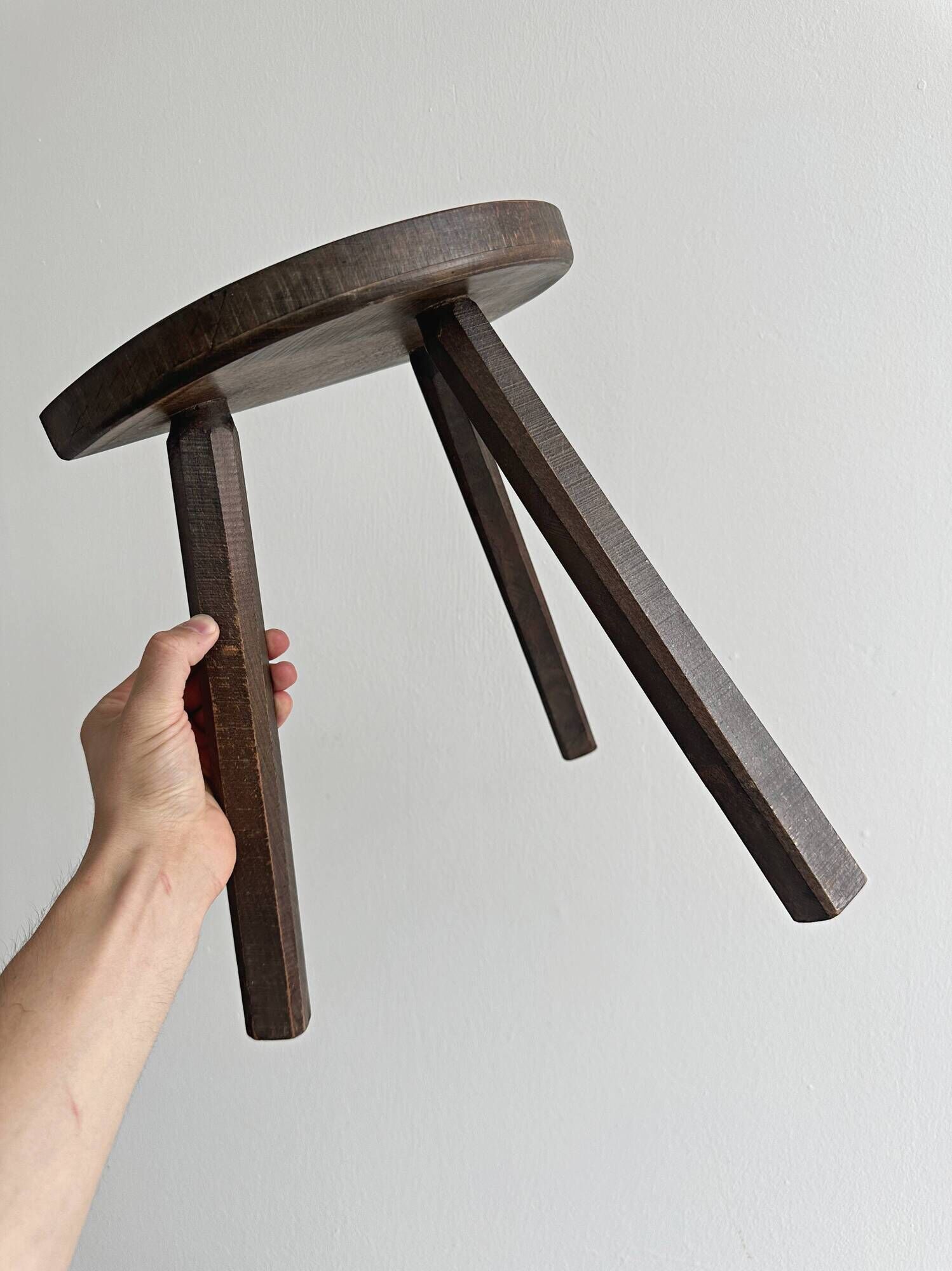 Antique wooden tripod stool with a semi-circular seat.