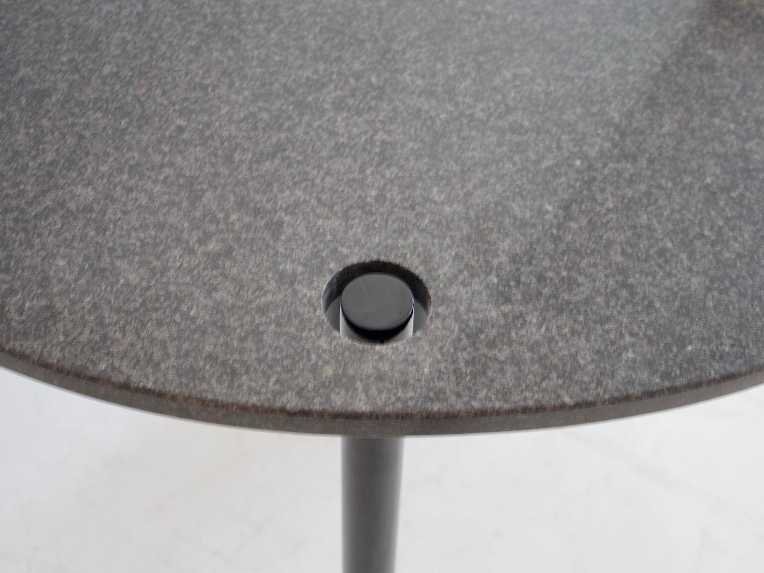 Round dining table in black lacquered metal with a granite top.