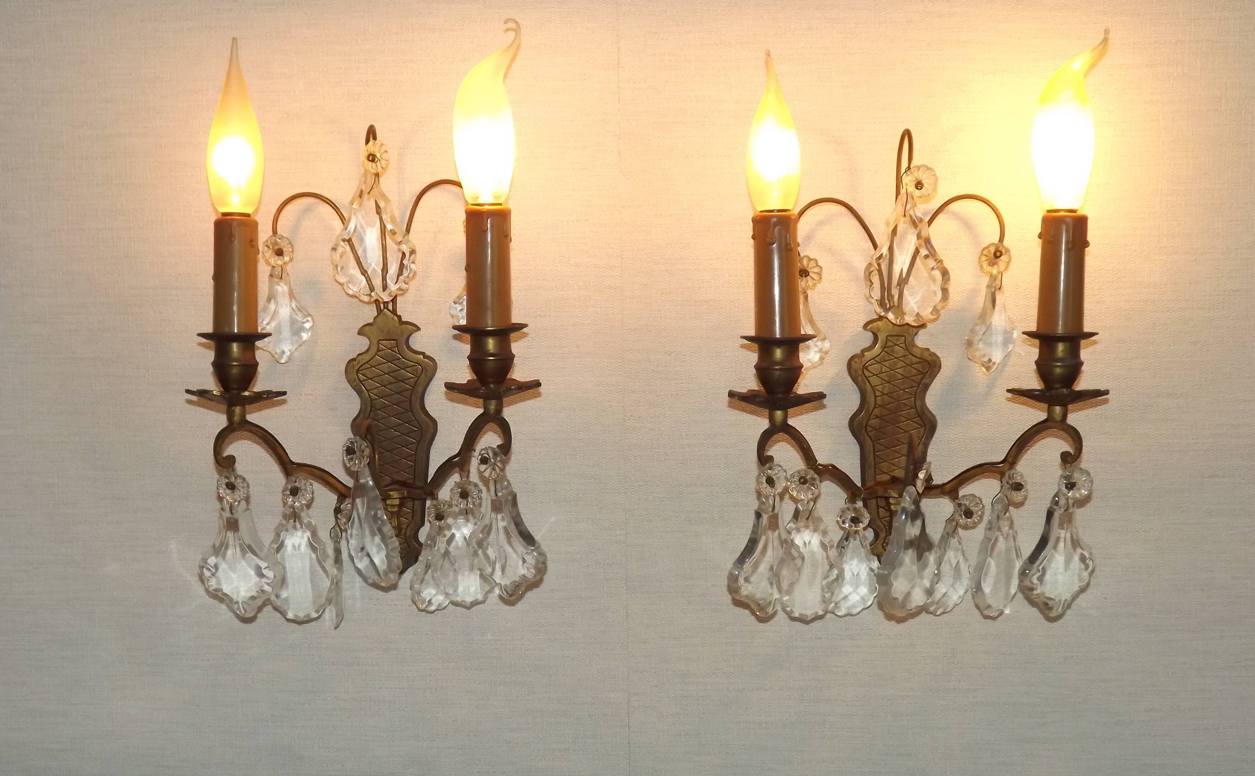 Pair of French antique brass double wall lights with assorted crystals.