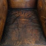 Fauteuil ancien en cuir de mouton sur roulettes et patiné
