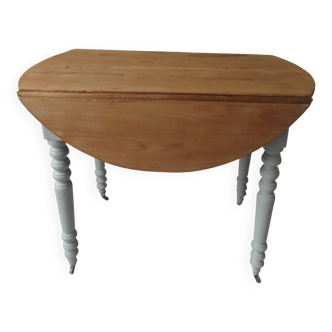 Walnut table with raised flaps, base on verdigris casters.