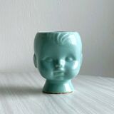 Turquoise plant pot in the shape of a vintage doll's head.