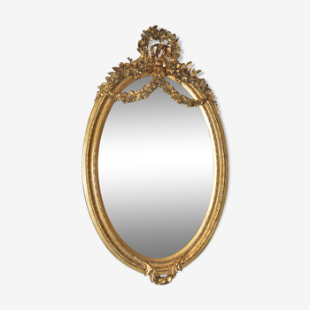 Miroir ovale doré avec un noeud et une couronne de fleurs