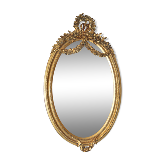 Golden oval mirror with a bow and a crown of flowers