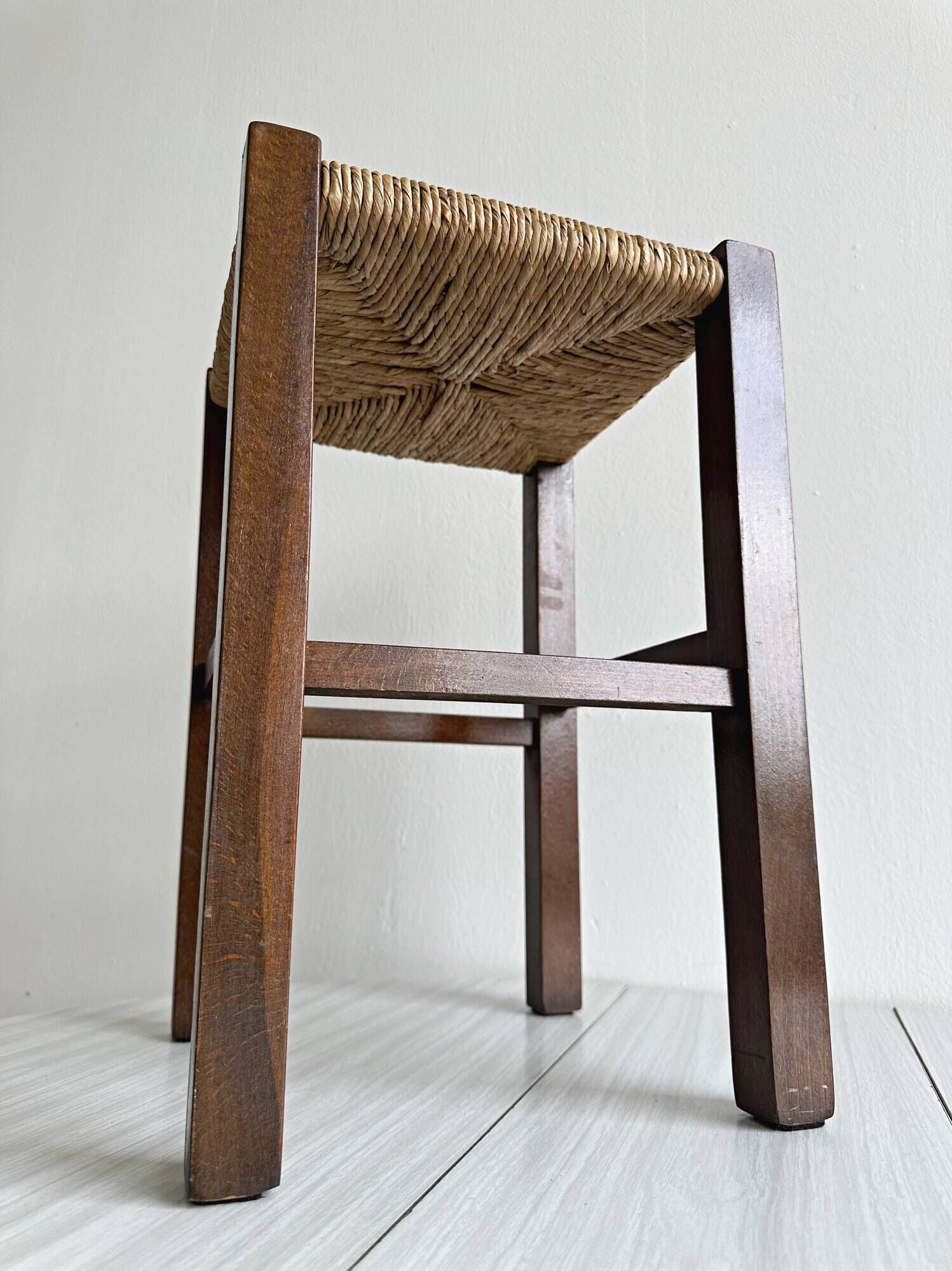 Vintage stool in dark wood with a woven straw seat.