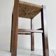 Vintage stool in dark wood with a woven straw seat.
