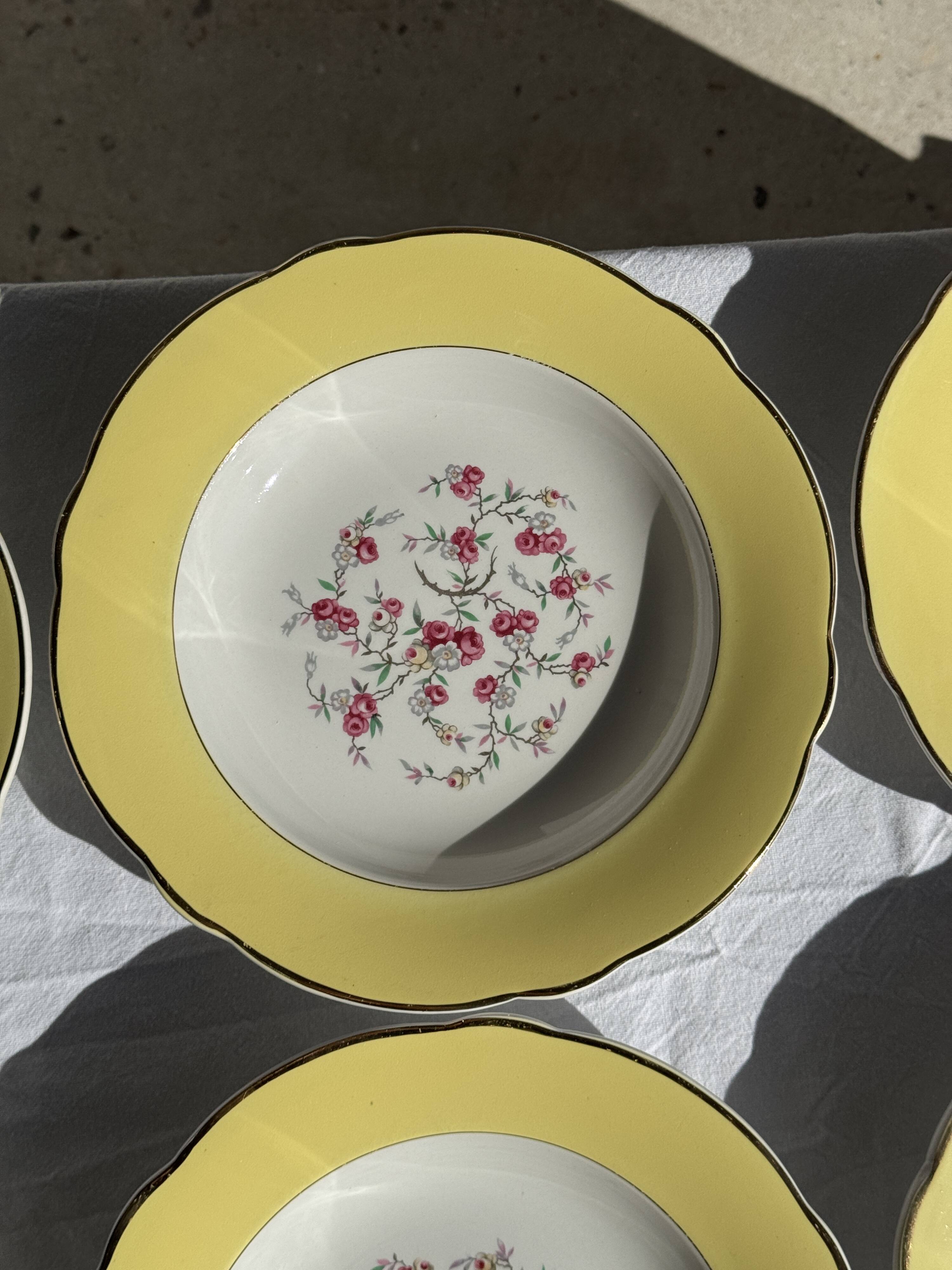 Set of 9 large vintage yellow deep plates with pink flowers and a gold rim.