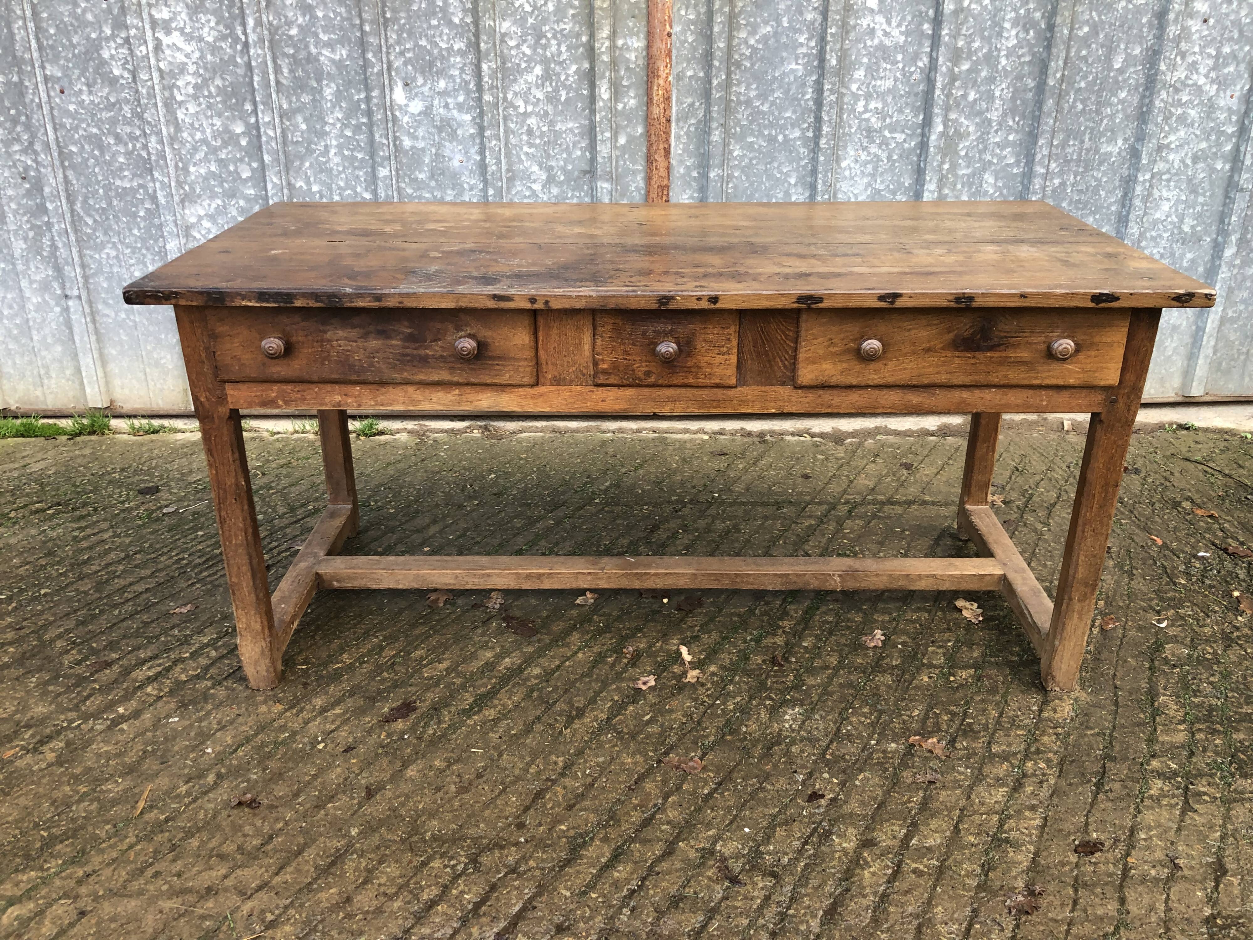 Old chestnut table with 3 front drawers and a cat bar.