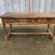 Old chestnut table with 3 front drawers and a cat bar.
