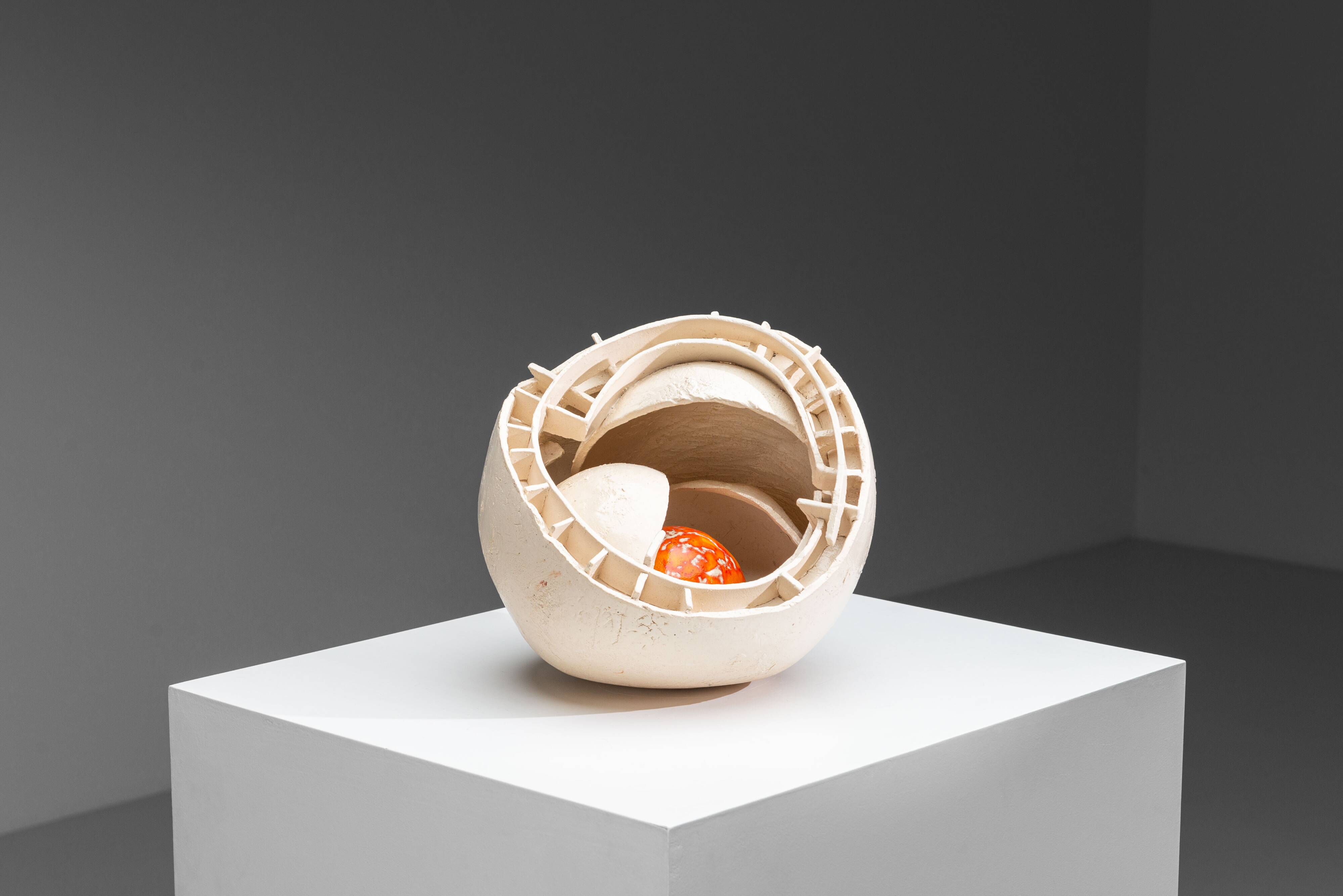 Sculpture en céramique abstraite avec un noyau orange.