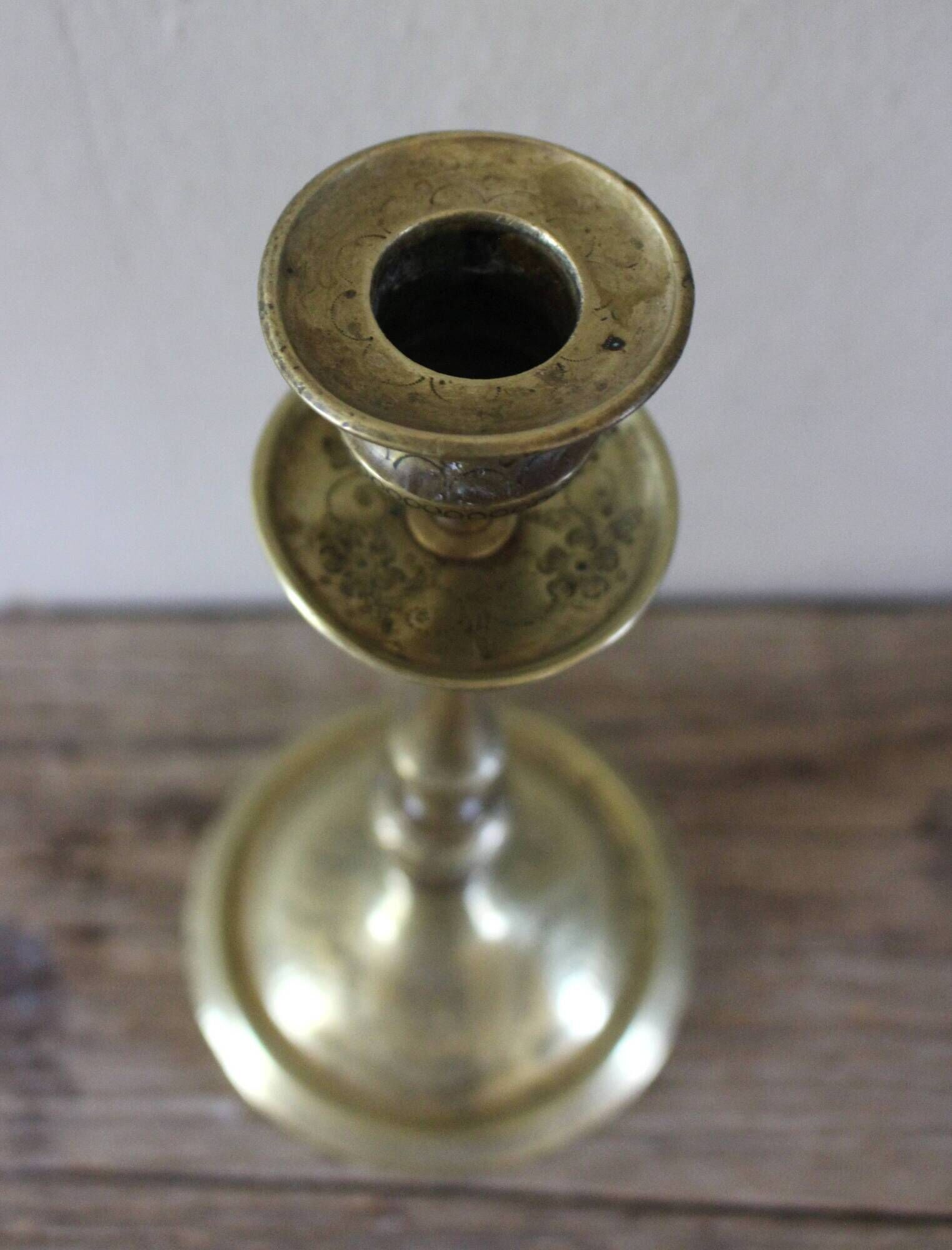 Brass candle holder with flowers and round shape.
