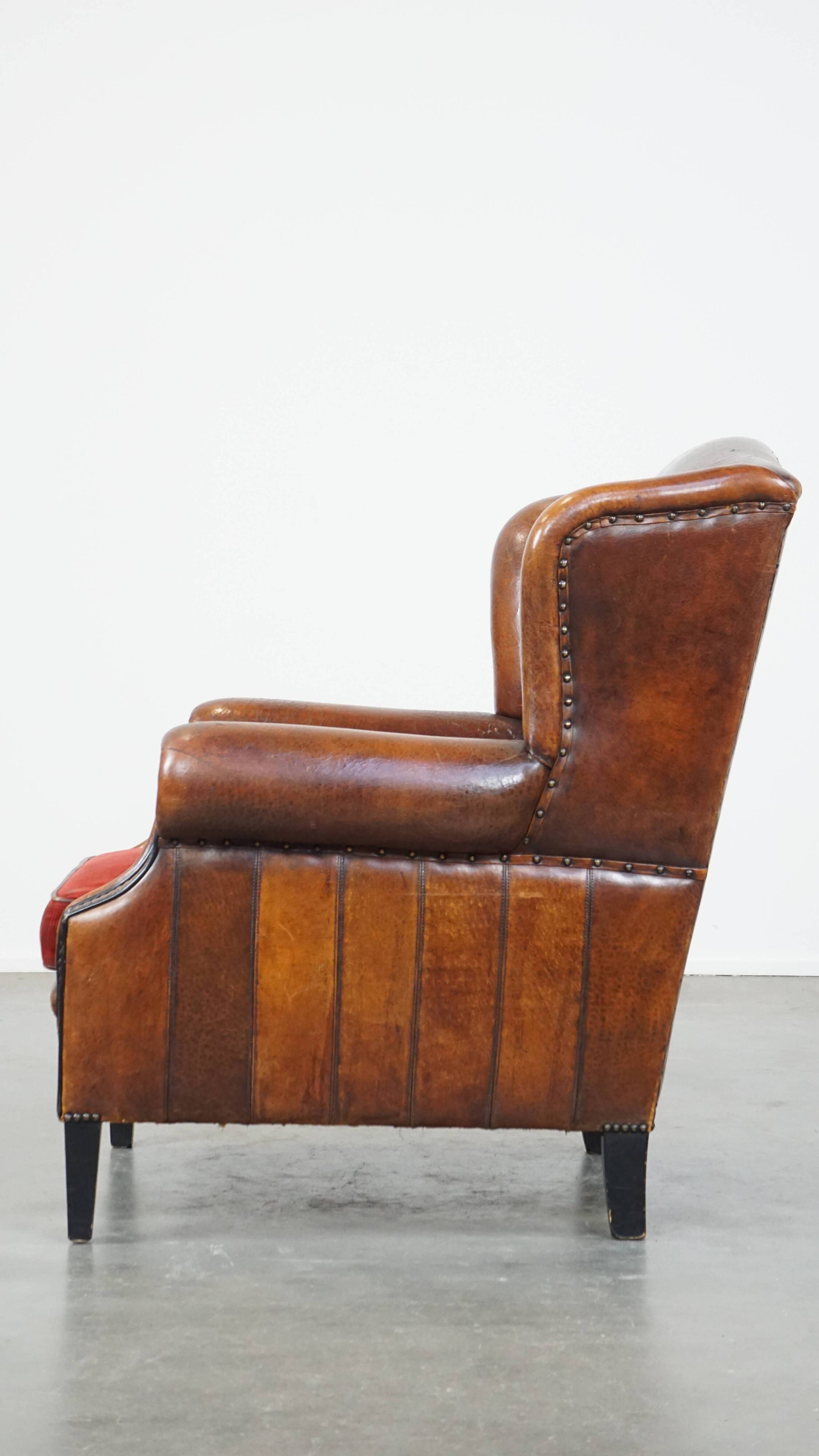Sheepskin leather wingback chair with a red corduroy seat cushion