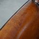 Cognac-colored sheepskin armchair with black piping and decorative nails
