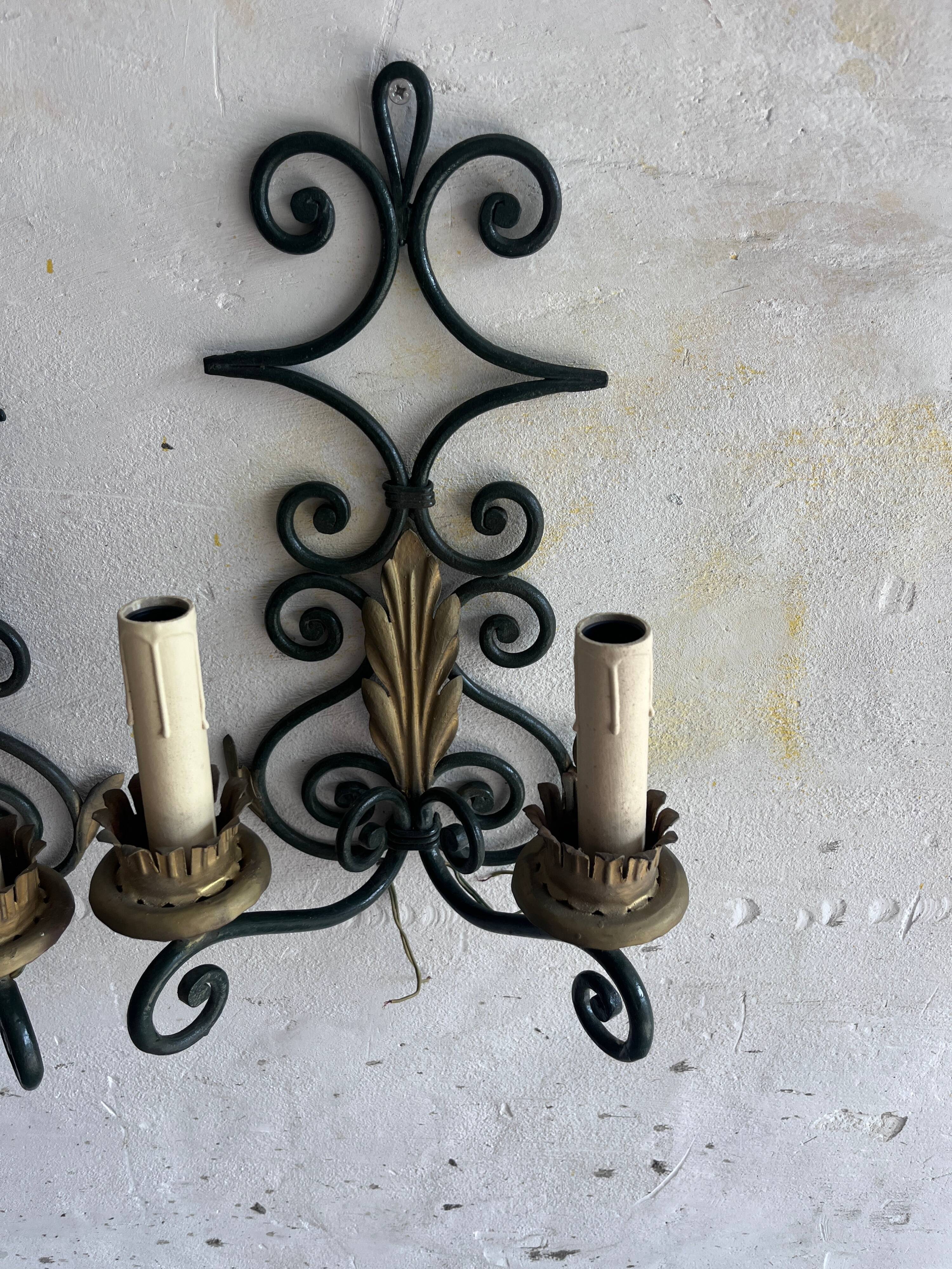Pair of wall sconces in wrought iron with golden leaf patterns.
