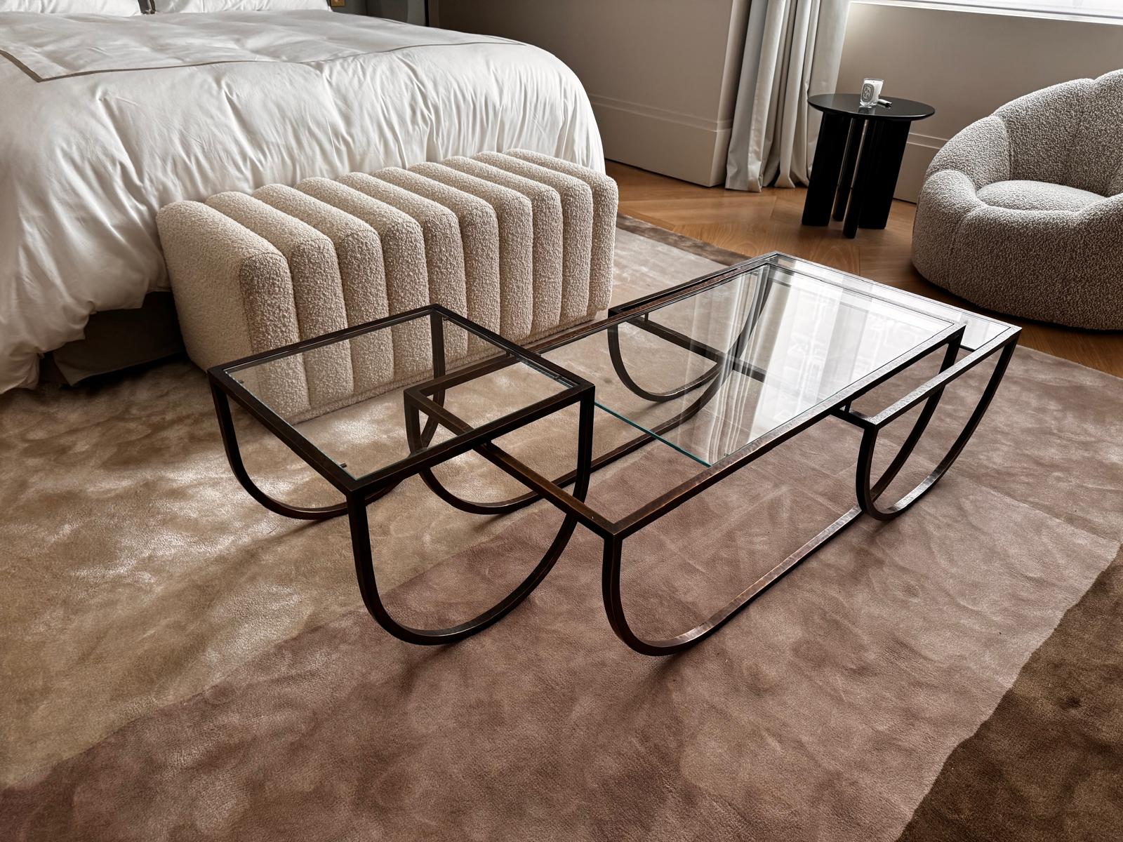 Asymmetrical metal-and-glass coffee table with curved architectural frame.
