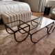Asymmetrical metal-and-glass coffee table with curved architectural frame.